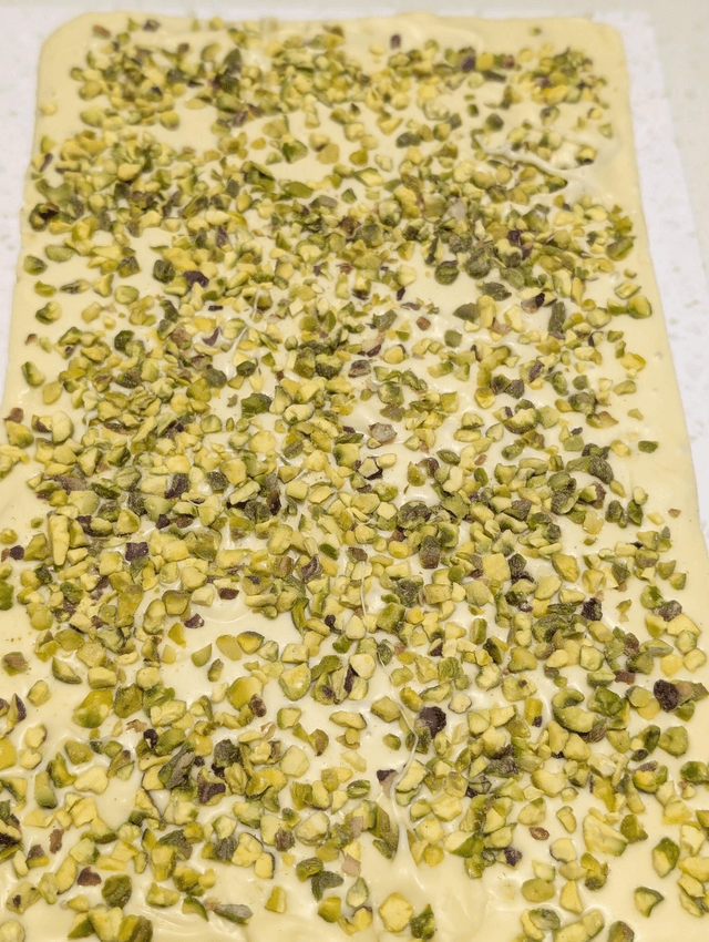 Giant, white chocolate, 750g bar filled with pistachio cream and feuillietine then topped with chopped pistachios.